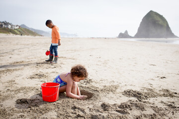 Girl and brother dig in sand at Haystack Rock