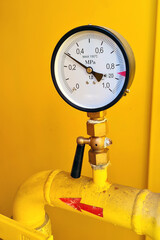 High pressure gauge meter or manometer installed to gas tube in yellow cabinet on industrial plant.