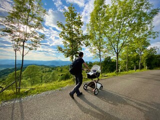 Father walking baby in a stroller on a beautiful day with gorgeous landscape in the background
