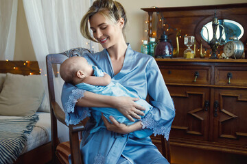 Young beautiful mother with her cute little baby wrapped in the blue cloth
