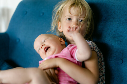 big sister holding wriggly baby sister