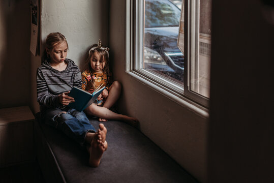 Brother and sister reading by window