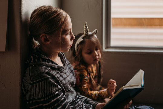 Siblings reading by window
