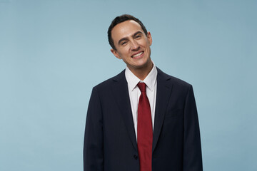 a man in a classic suit tilted his head to the side and a red tie around his neck