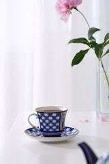 Fresh tea in a beautiful ceramic cup on a white table.