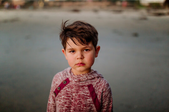 Serious clean-cut boy wearing sweatshirt at the beach