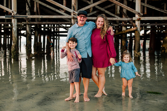 Happy family standing in sand near pier
