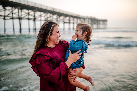 Laughing mom holding daughter in the ocean 
