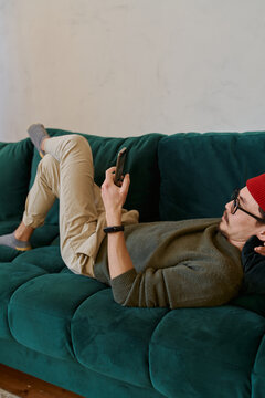 man chatting online smartphone on sofa at home