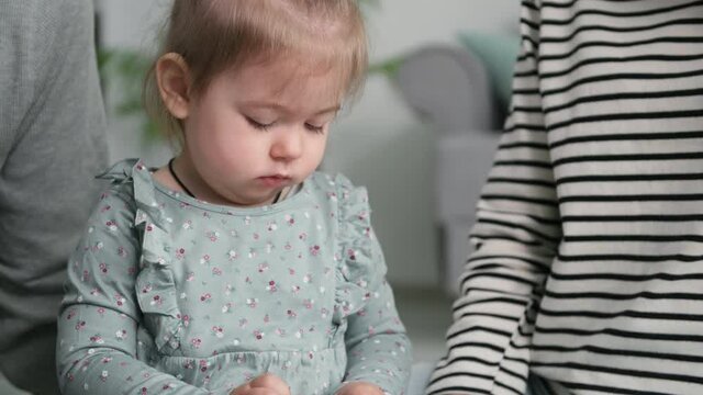 cute female child carefree play with her parents with plastic color constructor while sitting in the kids room