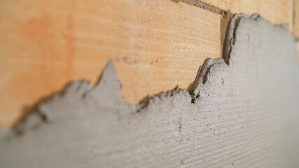 Leveling the wall with a finishing putty. Leveling the mortar on the wall with a construction trowel.