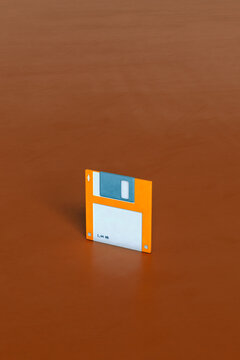 one single Blue and orange Floppy disks on brown background