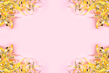 Shiny golden serpentine streamers on pink background with copy space. Top view, flat lay