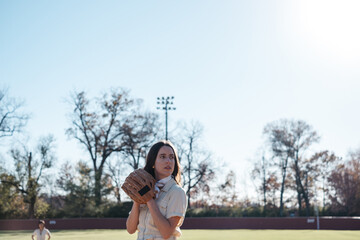 Stylish young girl getting ready to pitch the ball on a baseball field