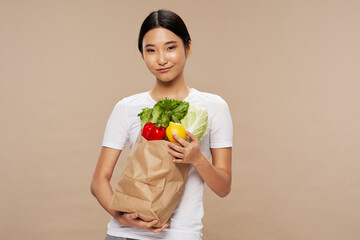 slim woman with package of groceries in hand on beige background cropped view of diet