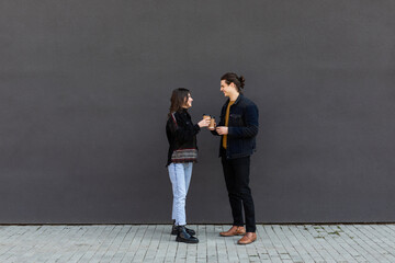 Couple. Man and woman crossing the street at the crosswalk while talking and drink coffee to go