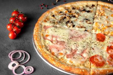 Italian pizza four seasons with cheese, ham, mushrooms, tomato, onion, pepperoni sausage on a gray...