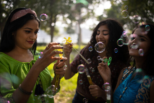 Three Indian girls enjoying bubbles at outdoors