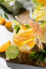 Refreshing lemonade with lemon and mint in a jug and glass on a wooden board. Summer drinks. Copy space.