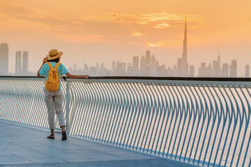 A happy traveler woman with a hat and a yellow backpack enjoys a stunning panoramic view of the...