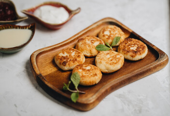 Syrniki served with sweet milk and jam on a white table.