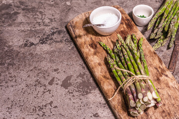 Bunch of fresh green asparagus on vintage wooden chopping board
