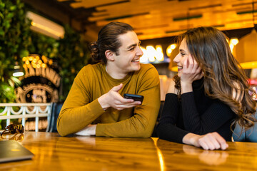 Young smiling couple in gorgeous restaurant looking at phone.