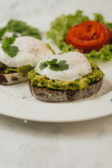 Poached eggs with avocado on sourdough toasts on white background