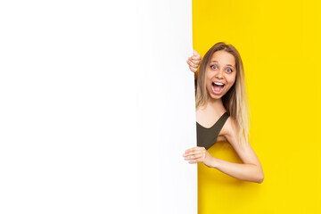 Banner. A young caucasian happy smiling pretty blonde woman holds on to the white board with her...
