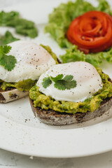 Poached eggs with avocado on sourdough toasts on white background