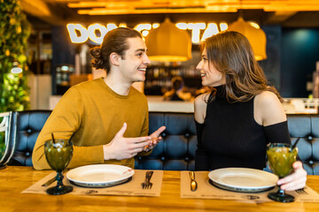 Young serious man having conversation with woman girlfriend sit at cafe table.