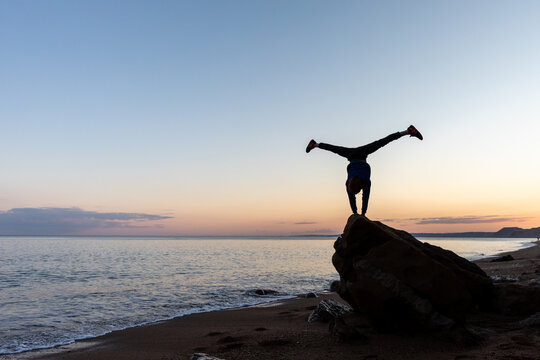 Boy performing a handstand on a rock