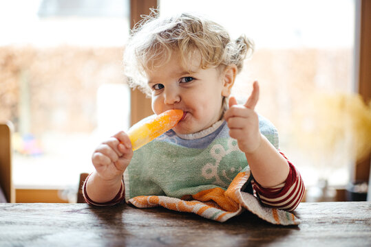 Toddler girl eating an ice cold popsicle