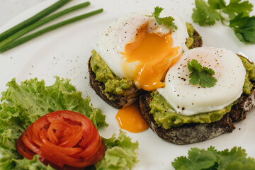 Poached eggs with avocado on sourdough toasts on white background