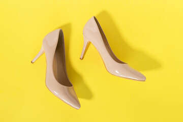 Classic beige women's shoes with medium heels on a yellow background. The concept of sales and...