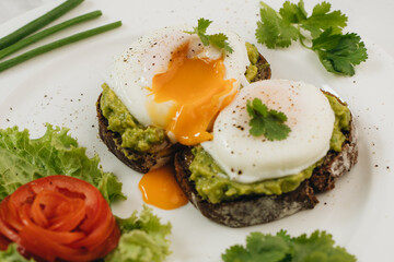 Poached eggs with avocado on sourdough toasts on white background