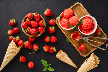 Heap of strawberry with ice cream in ice cream paper cups and cones. Strawberry sorbet on black...