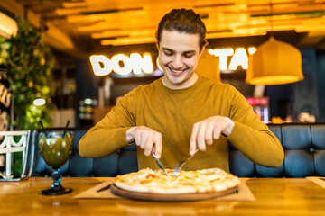 Close-up view of happy man eating pizza in cafe