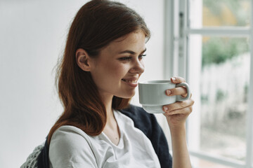woman at home near the window with a cup of coffee rest smile