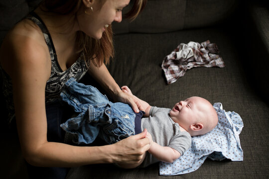 Mother smiles while dressing happy infant