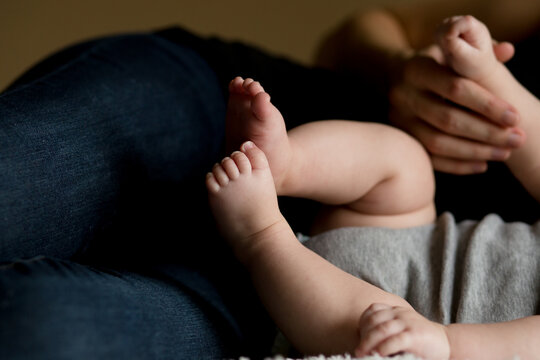 Faceless image of baby legs and feet next to parent