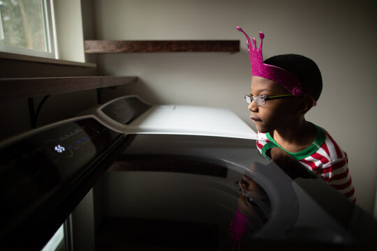 Boy in pink crown looks out window