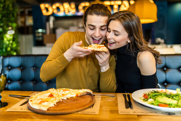 Young couple sitting in a restaurant eating pizza