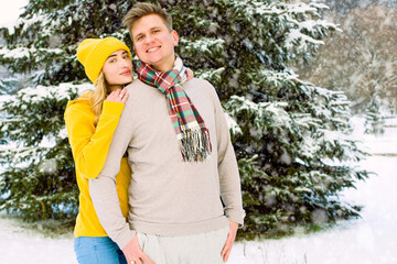 Beautiful winter couple posing against the background of a winter forest and a lot of snow