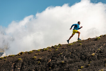 Sportsman running in mountains on foggy day 