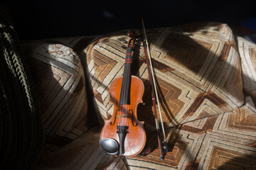 photo of a violin on a couch in a sunny patch 