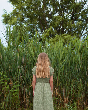 Girl Standing by Tall Green Grass