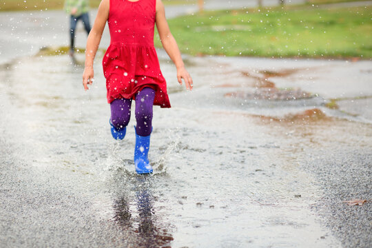 Girl runs through puddle splashing up water
