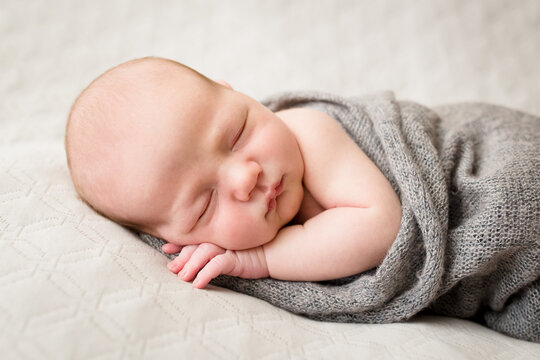 Closeup portrait of sleeping baby in gray wrap