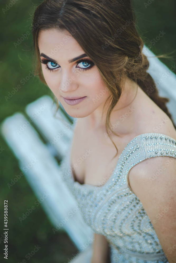 Poster Young woman with evening makeup sitting on the bench